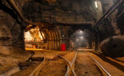 Tunnel of the mining of an underground mine. Lots of pipelines on the ceiling and rail track for trolleys