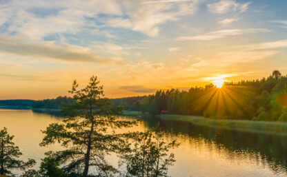 Panorama picture taken in Sweden with sunset over a lake and beautiful glow from the sun
