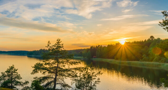 Panorama picture taken in Sweden with sunset over a lake and beautiful glow from the sun